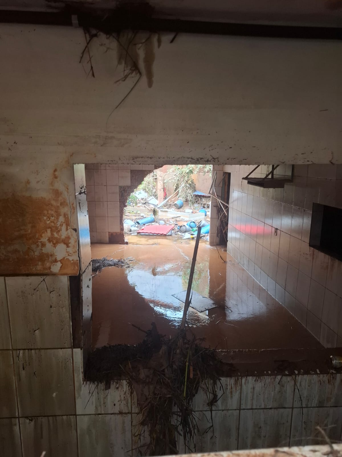 View through a flooded corridor showing debris and standing water outside